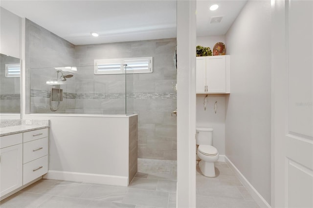 bathroom with vanity, tile patterned flooring, toilet, and tiled shower