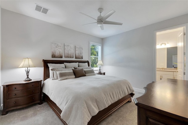 bedroom featuring ceiling fan, light carpet, and ensuite bath