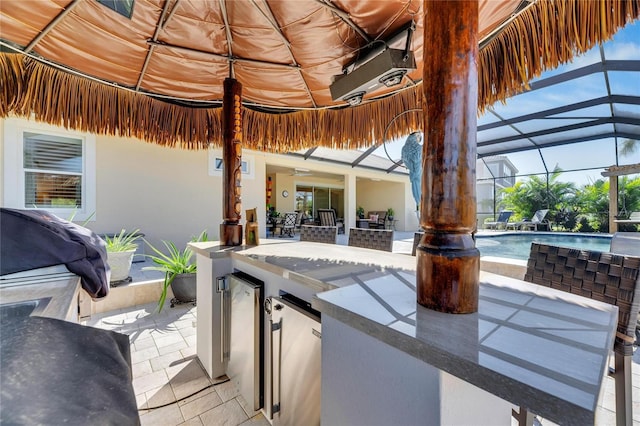 view of patio / terrace with grilling area, an outdoor kitchen, exterior bar, and glass enclosure