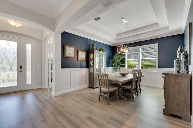 dining room featuring a notable chandelier, a tray ceiling, light hardwood / wood-style flooring, and ornamental molding