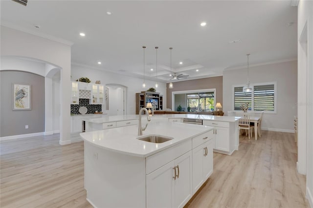 kitchen with pendant lighting, sink, ceiling fan, and a center island with sink