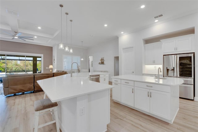 kitchen featuring appliances with stainless steel finishes, decorative light fixtures, white cabinetry, a large island, and beam ceiling