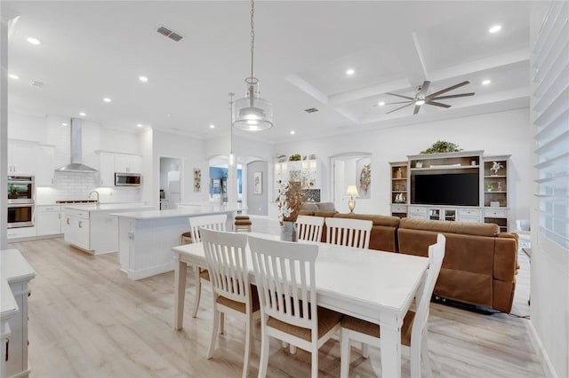 dining space with coffered ceiling, ceiling fan, light hardwood / wood-style flooring, and beamed ceiling