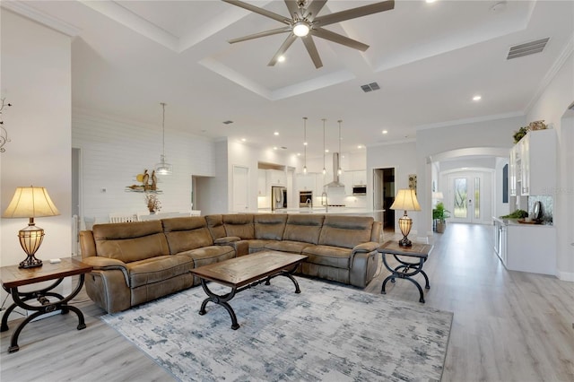 living room with coffered ceiling, light hardwood / wood-style flooring, ornamental molding, ceiling fan, and beam ceiling