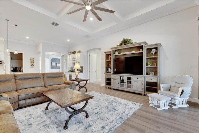 living room featuring ceiling fan, coffered ceiling, ornamental molding, light hardwood / wood-style floors, and beamed ceiling