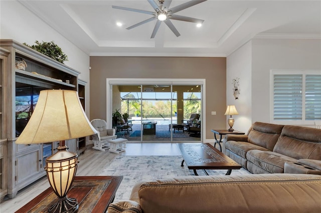 living room with crown molding, ceiling fan, a raised ceiling, and light hardwood / wood-style flooring