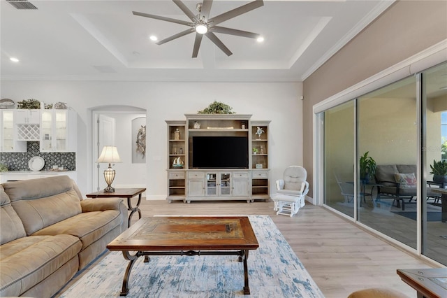 living room featuring light hardwood / wood-style floors, ceiling fan, and a tray ceiling