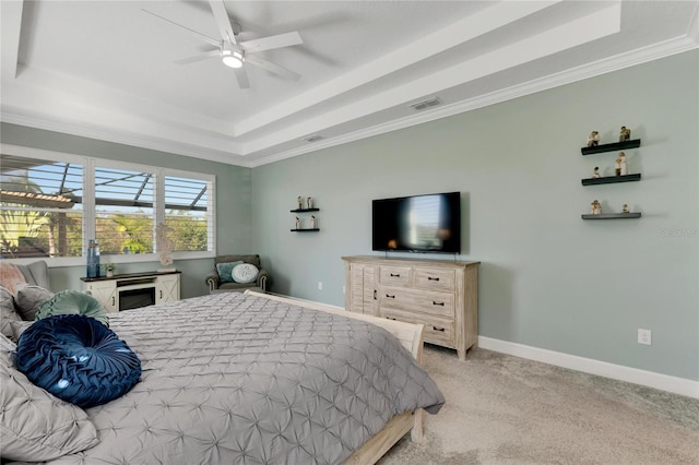 bedroom with ceiling fan, ornamental molding, a tray ceiling, and light colored carpet