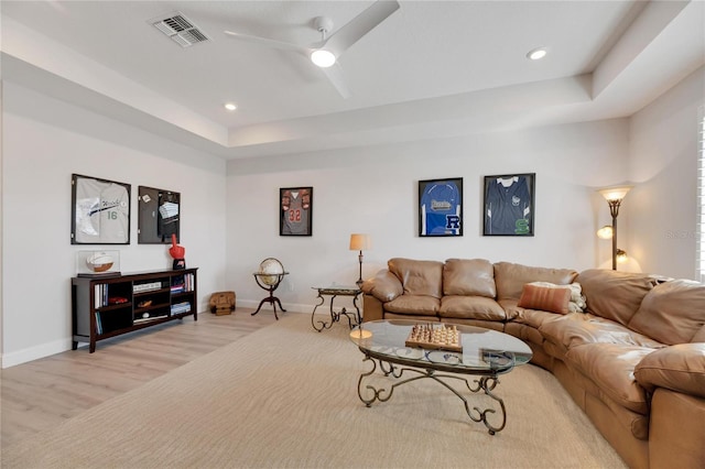 living room with ceiling fan, a raised ceiling, and light hardwood / wood-style floors