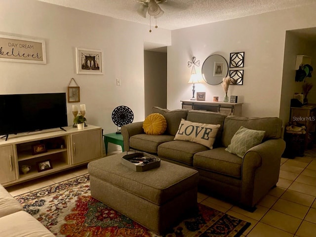 living room with a textured ceiling, ceiling fan, and light tile patterned flooring