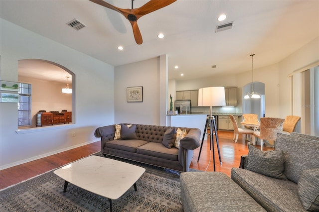 living room with wood-type flooring and ceiling fan with notable chandelier