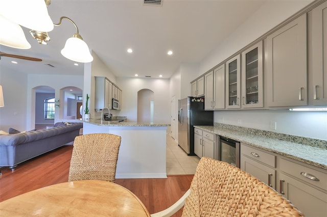 kitchen with light hardwood / wood-style flooring, light stone countertops, pendant lighting, beverage cooler, and gray cabinets