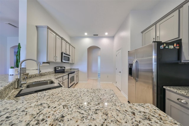 kitchen featuring light tile patterned floors, light stone countertops, sink, gray cabinets, and stainless steel appliances