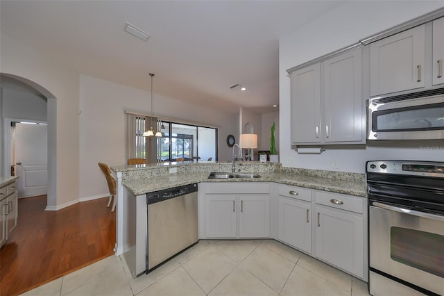 kitchen with light stone countertops, appliances with stainless steel finishes, sink, and kitchen peninsula