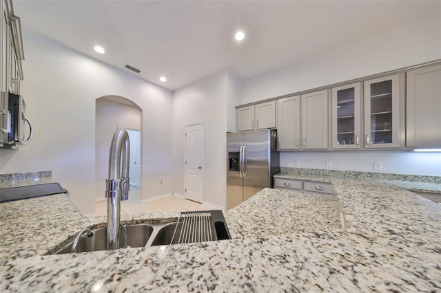 kitchen with light tile patterned floors, appliances with stainless steel finishes, sink, gray cabinets, and light stone counters