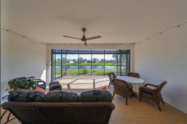 sunroom / solarium featuring a water view and ceiling fan