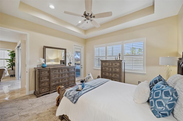 bedroom featuring multiple windows, a tray ceiling, and ceiling fan