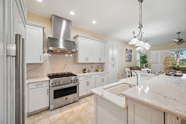 kitchen featuring a center island with sink, stainless steel range, wall chimney range hood, pendant lighting, and white cabinetry