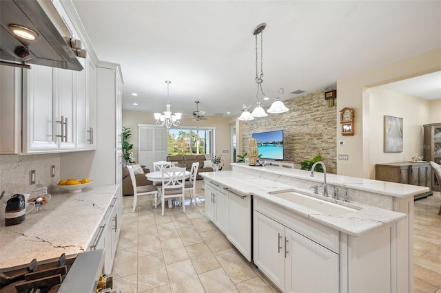 kitchen with hanging light fixtures, light stone countertops, a kitchen island, sink, and white cabinetry