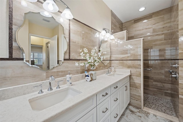 bathroom featuring tile walls, tiled shower, and vanity