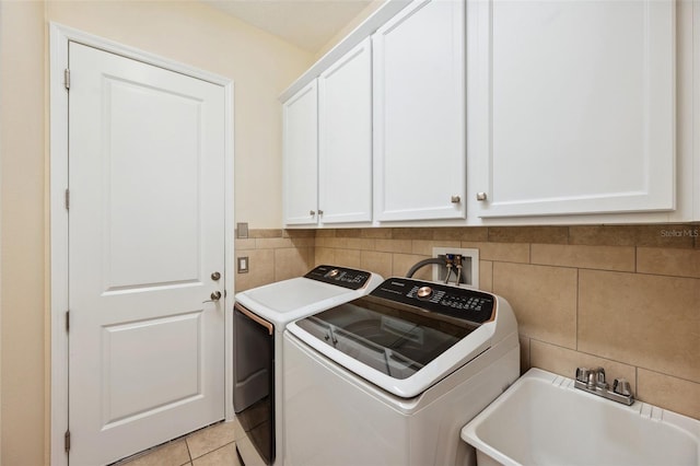 laundry area with cabinets, sink, tile walls, light tile patterned flooring, and washer and clothes dryer