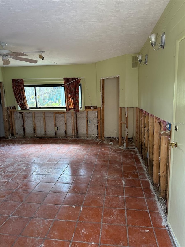 tiled empty room featuring ceiling fan and a textured ceiling