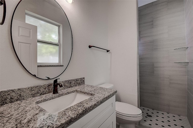 bathroom with vanity, tiled shower, and toilet