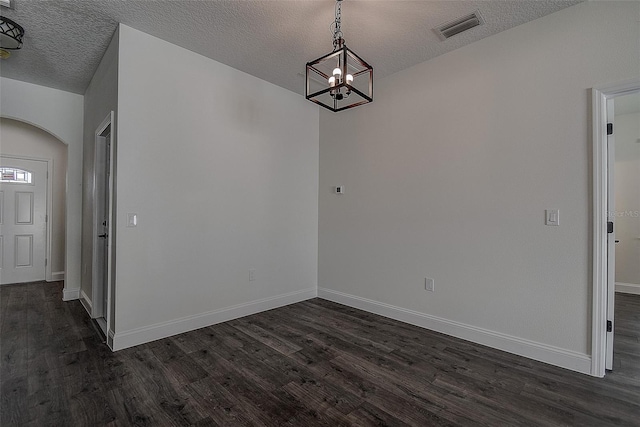 unfurnished dining area featuring a textured ceiling, a chandelier, and dark wood-type flooring