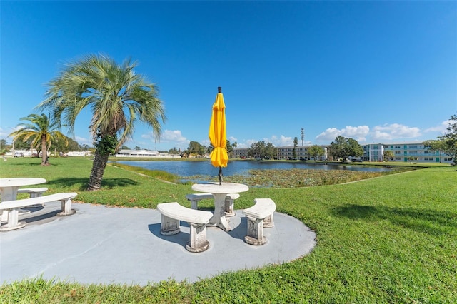 view of property's community featuring a patio, a lawn, and a water view