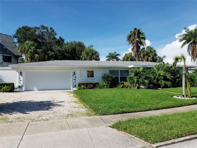 ranch-style home with an attached garage, stucco siding, a front yard, and gravel driveway