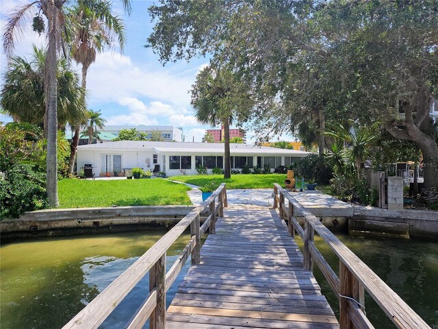 view of dock with a lawn and a water view