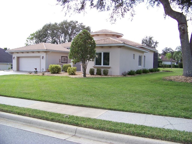 mediterranean / spanish home featuring a front yard and a garage