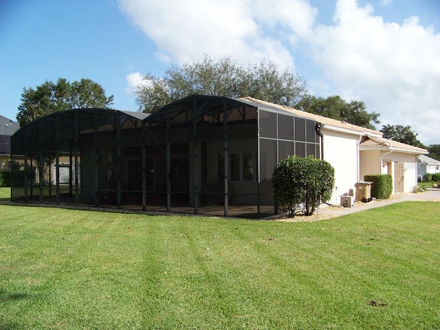 view of side of property with a yard and glass enclosure