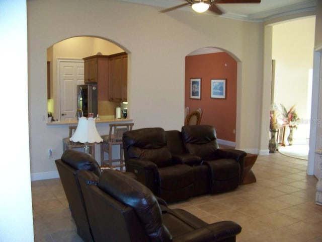 tiled living room with crown molding and ceiling fan