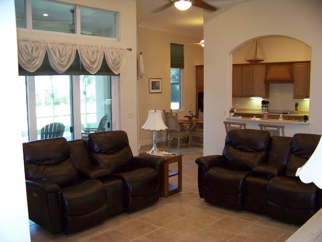 living room with crown molding, light tile patterned flooring, and ceiling fan