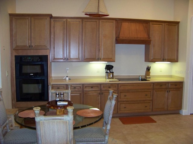 kitchen featuring custom exhaust hood, black double oven, cooktop, and light tile patterned floors