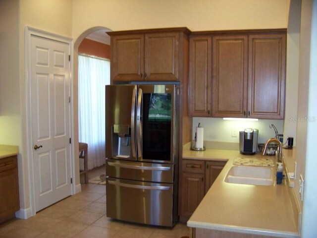 kitchen with sink, light tile patterned floors, ornamental molding, and stainless steel fridge with ice dispenser