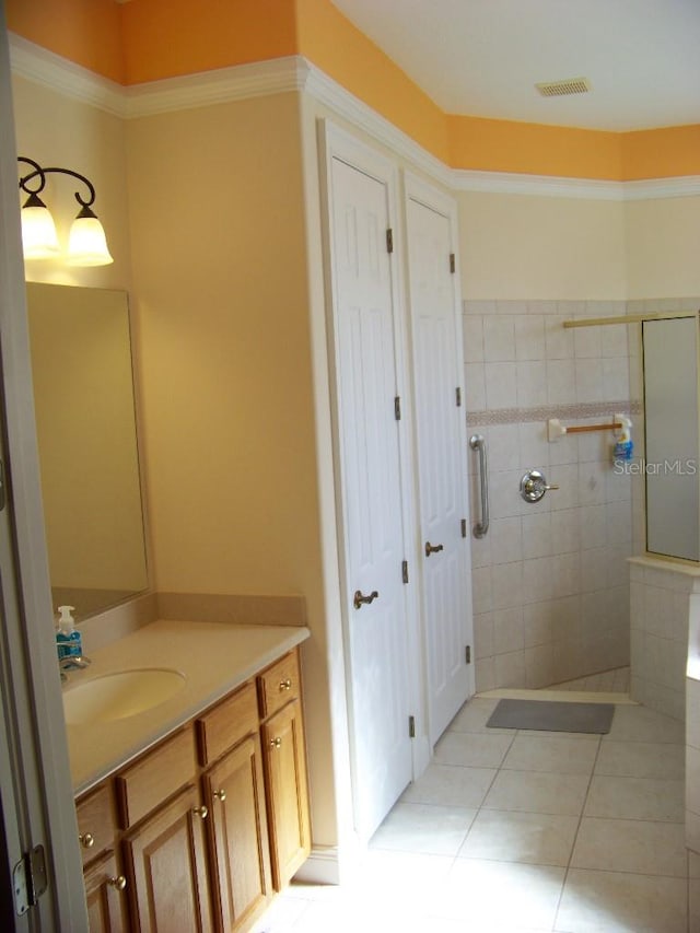 bathroom with vanity, tiled shower, and tile patterned flooring