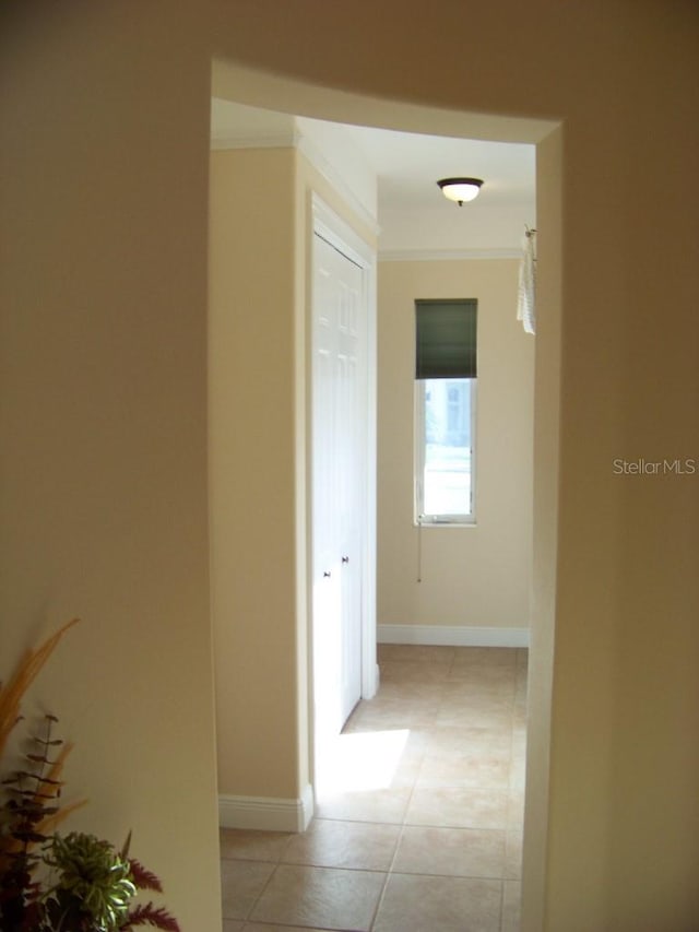 hall featuring ornamental molding and light tile patterned flooring