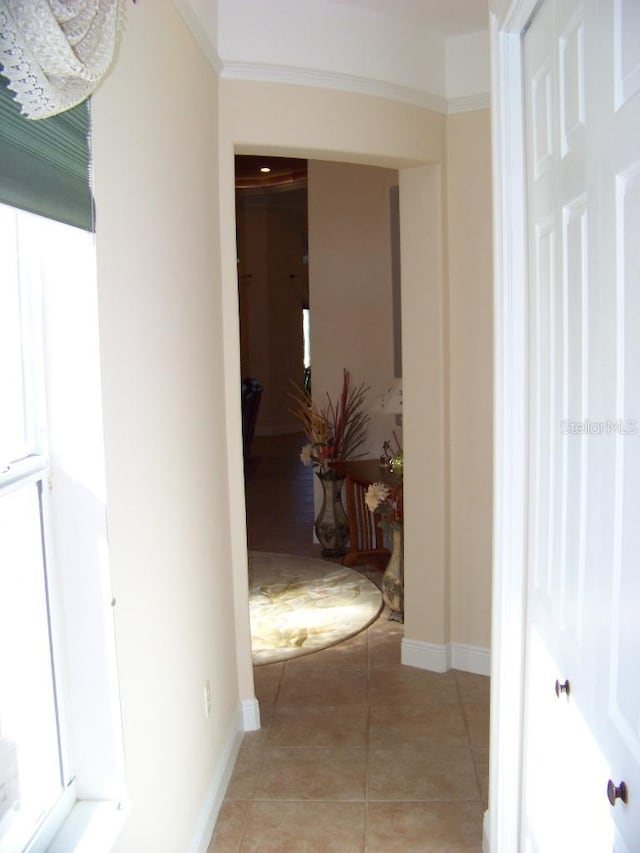 hall with ornamental molding and light tile patterned floors