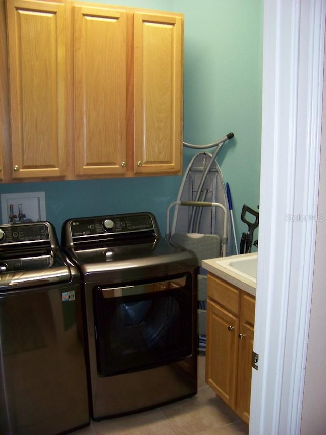 washroom with sink, independent washer and dryer, light tile patterned flooring, and cabinets