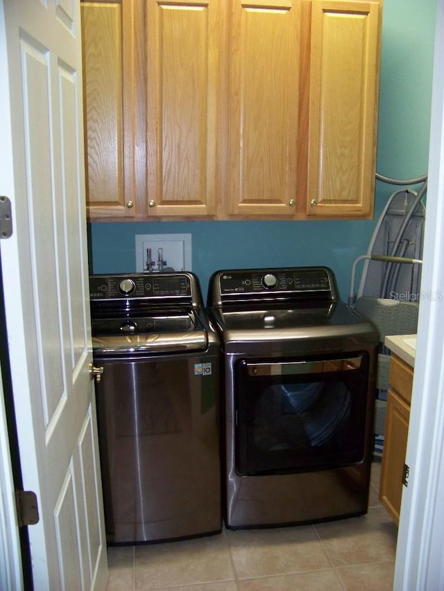 laundry area featuring light tile patterned floors, separate washer and dryer, and cabinets