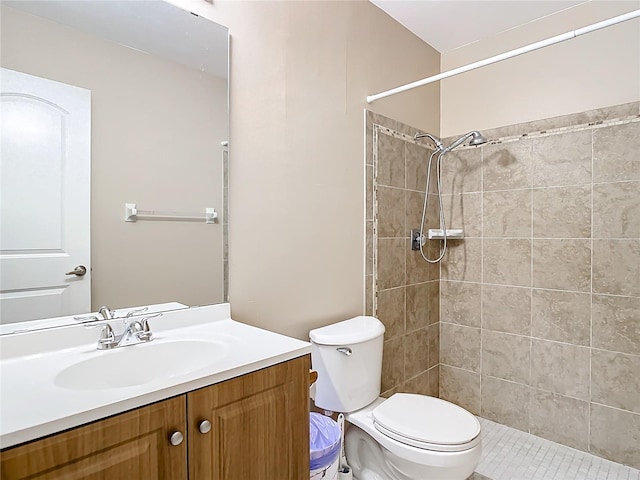 bathroom with tile patterned floors, vanity, toilet, and a tile shower