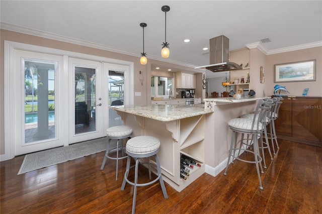 kitchen featuring island exhaust hood, hanging light fixtures, dark hardwood / wood-style flooring, light stone countertops, and ornamental molding