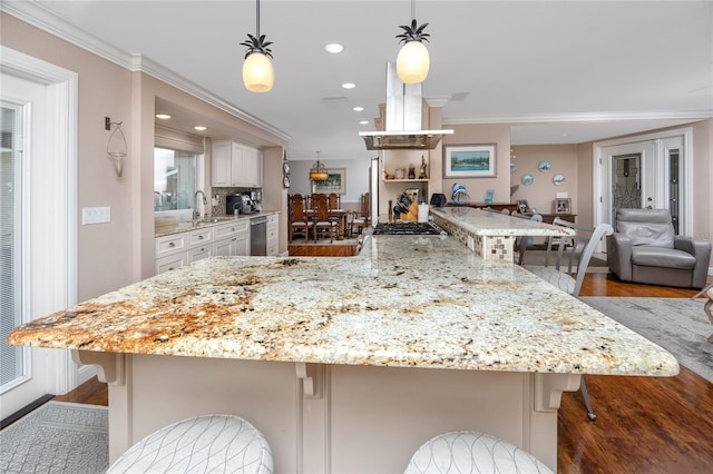 kitchen with a breakfast bar, ornamental molding, wood-type flooring, and pendant lighting