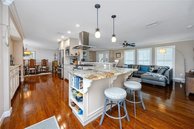 kitchen featuring stainless steel fridge, dark hardwood / wood-style flooring, a breakfast bar area, island range hood, and pendant lighting