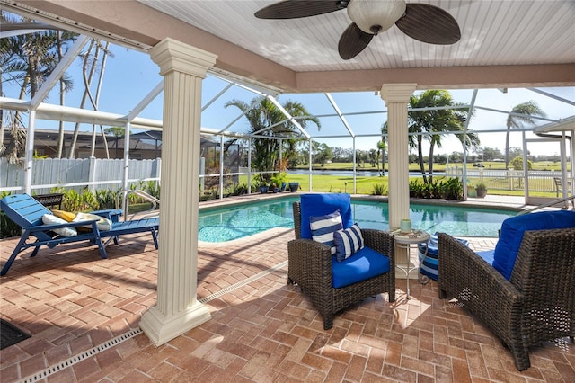 view of swimming pool with a patio area, glass enclosure, and ceiling fan