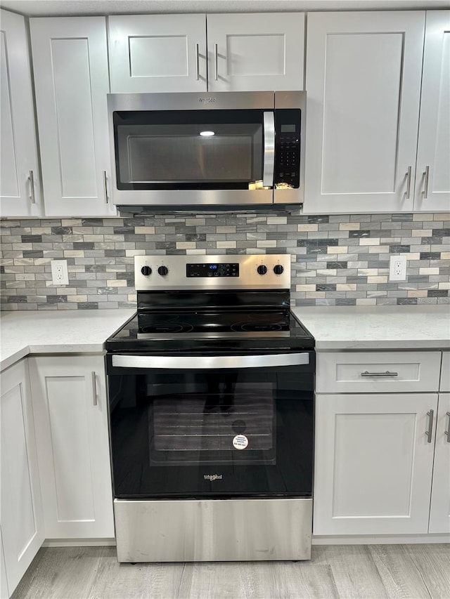 kitchen featuring white cabinetry, backsplash, stainless steel appliances, and light hardwood / wood-style flooring