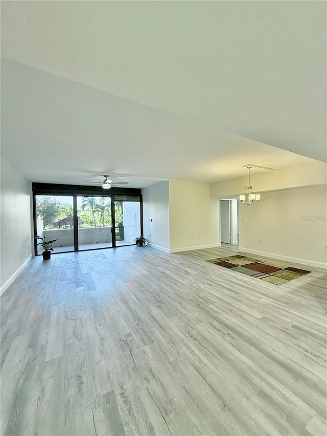 unfurnished living room with ceiling fan with notable chandelier and light hardwood / wood-style floors