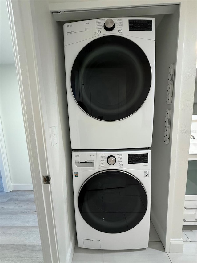 laundry area featuring light hardwood / wood-style flooring and stacked washing maching and dryer